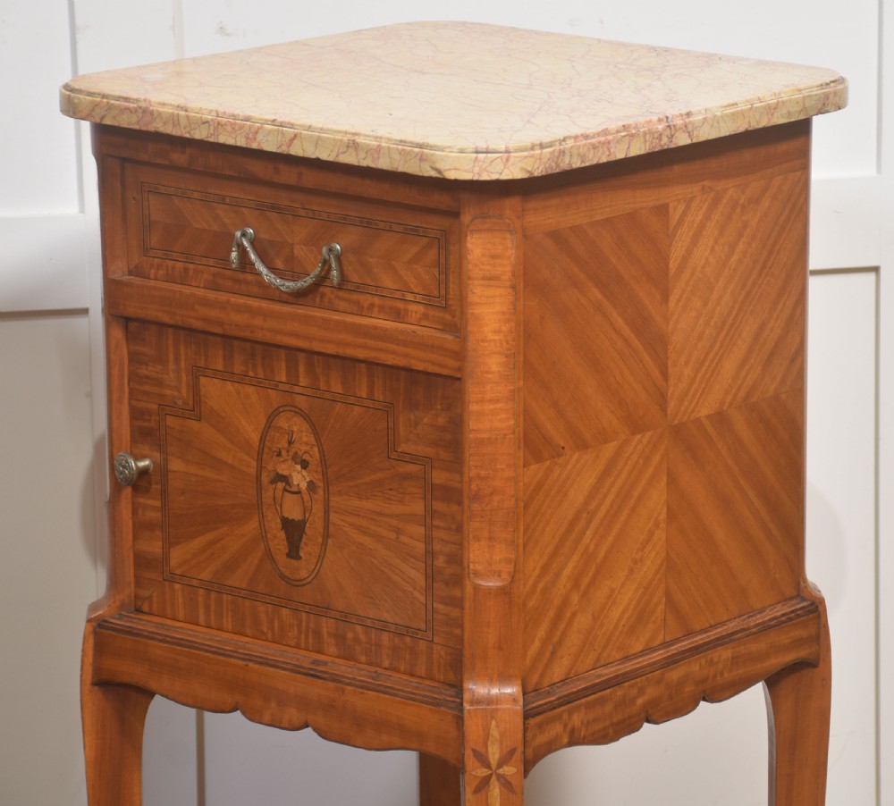 A pair of tall French satinwood bedside cabinets with marble tops, marquetry oval medallions, drawers, and slender legs. View VI