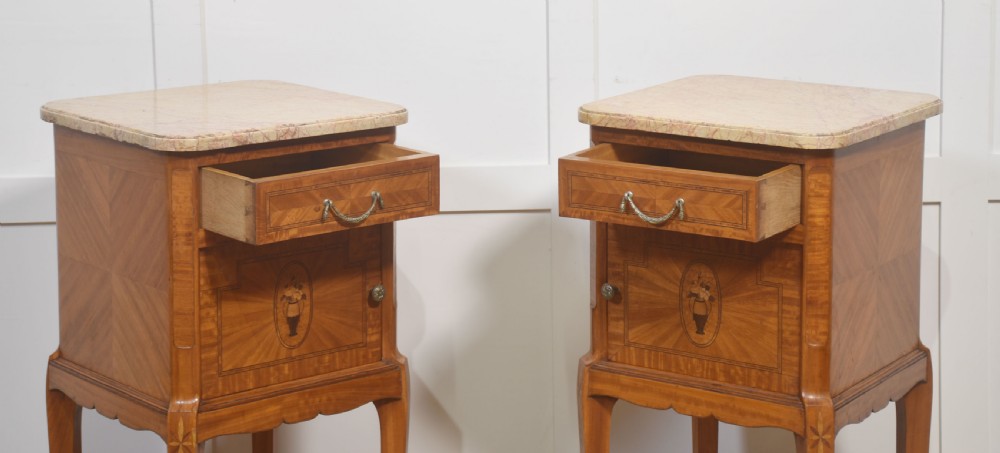 A pair of tall French satinwood bedside cabinets with marble tops, marquetry oval medallions, drawers, and slender legs. View IX