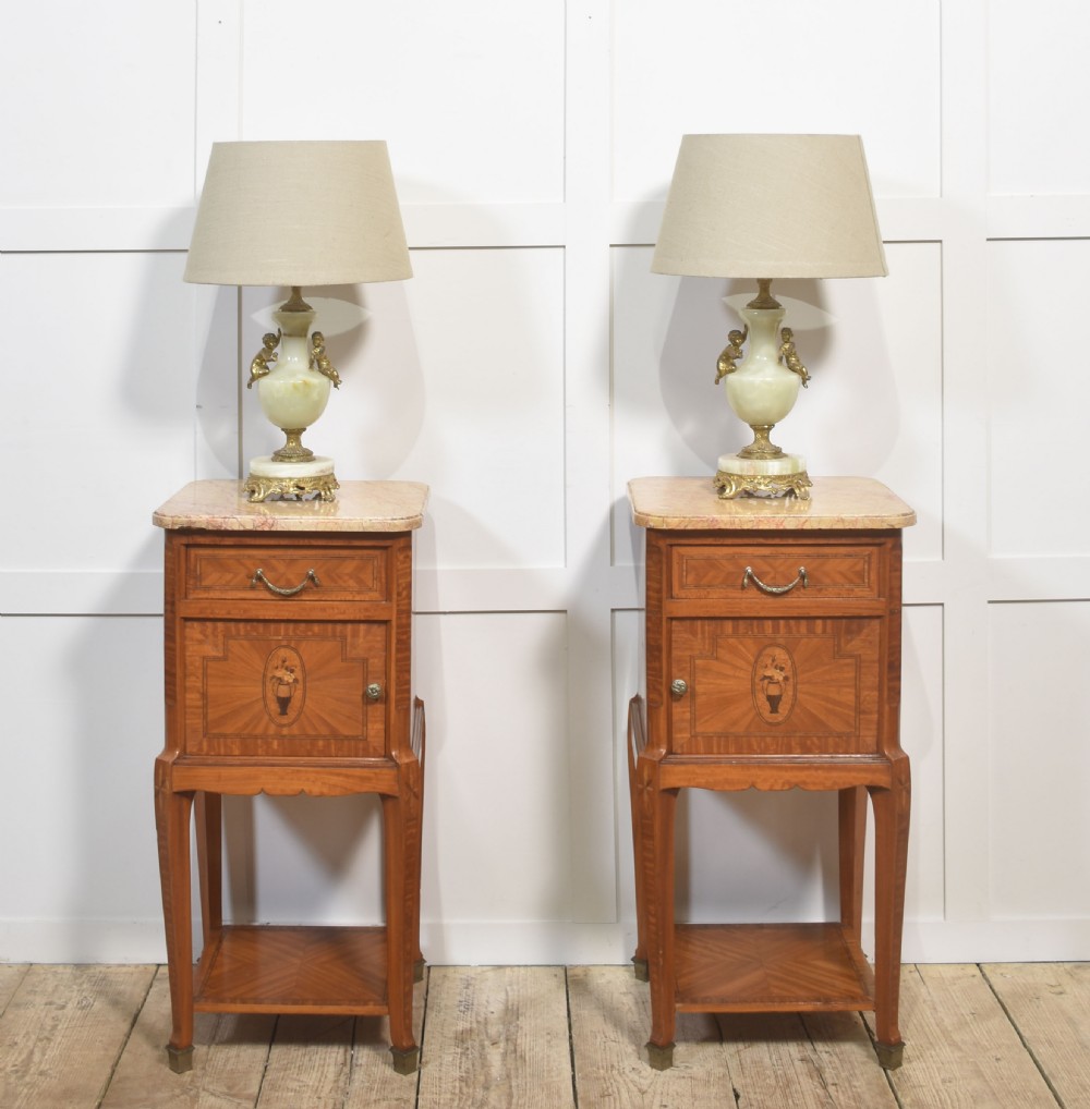 A pair of tall French satinwood bedside cabinets with marble tops, marquetry oval medallions, drawers, and slender legs. View XII