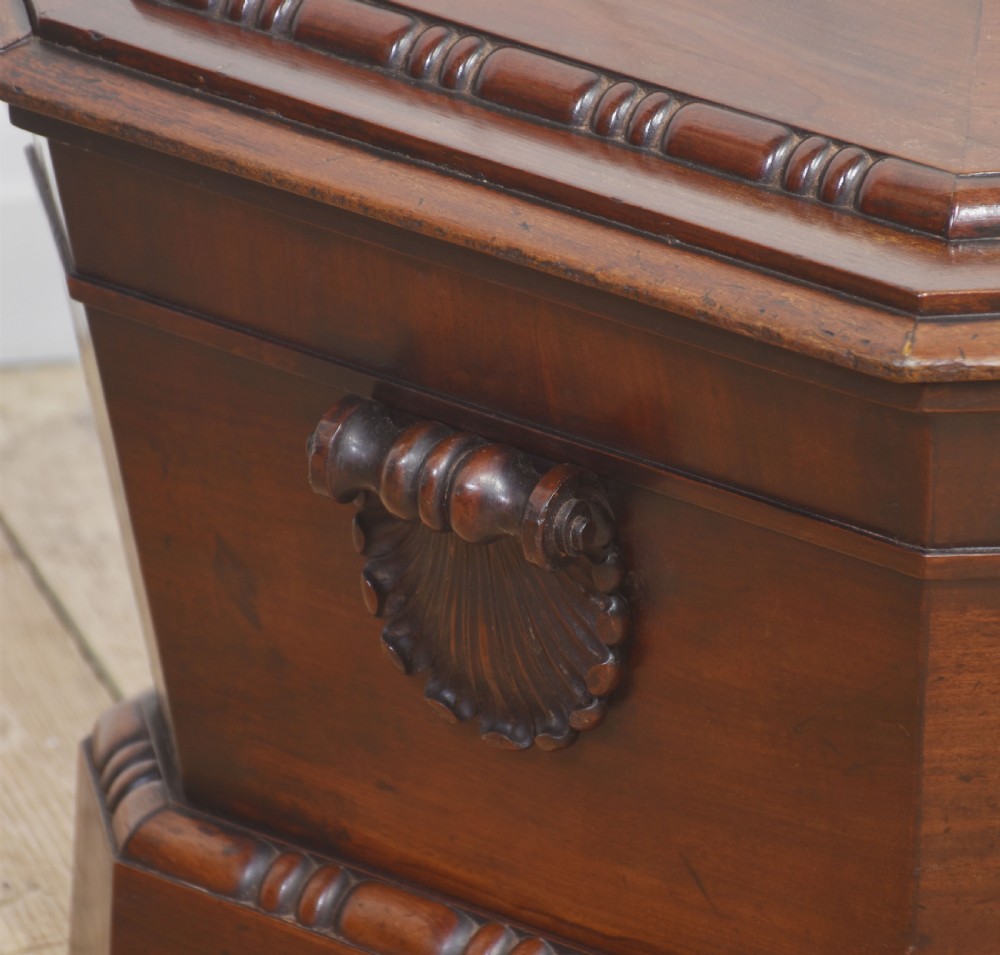A Georgian dark mahogany sarcophagus-shaped cellarette featuring carved gadrooning around the lid and base, side handles, and a central keyhole. View III