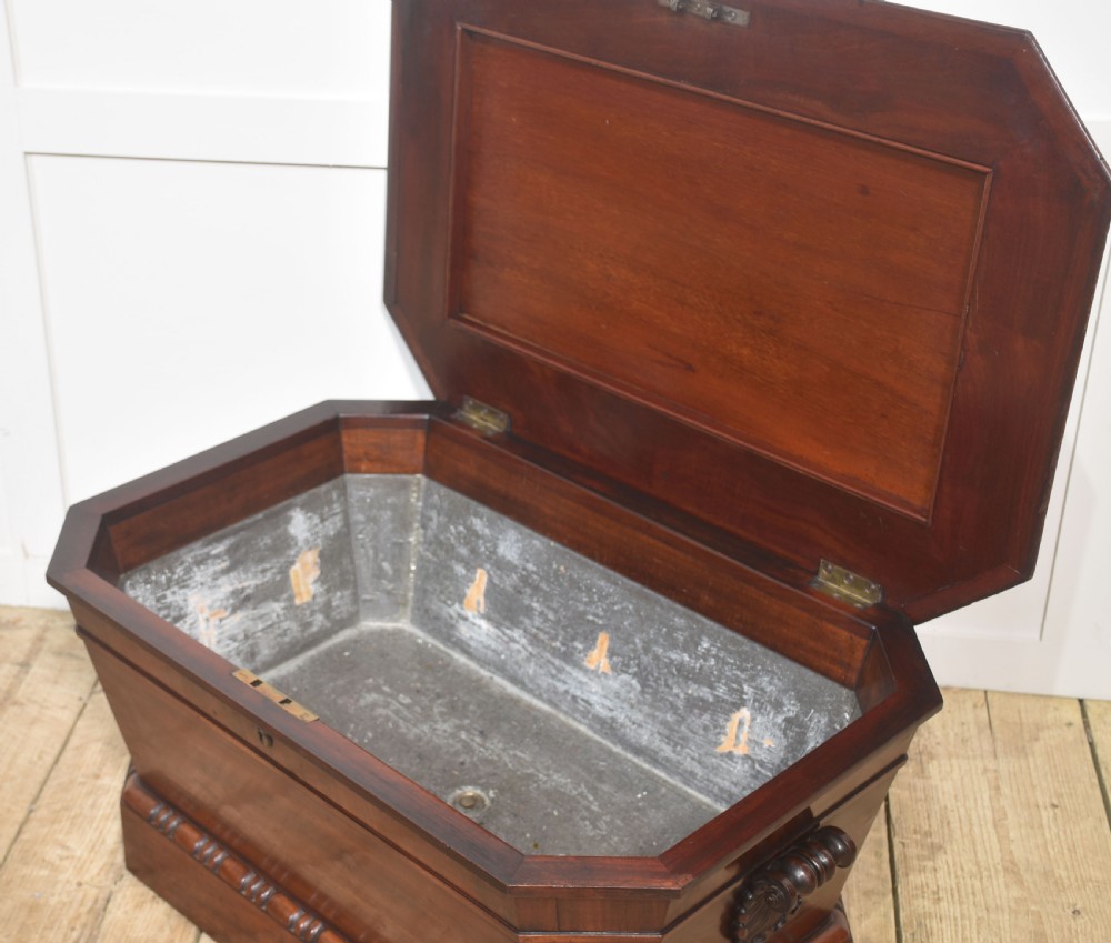 A Georgian dark mahogany sarcophagus-shaped cellarette featuring carved gadrooning around the lid and base, side handles, and a central keyhole. View VI