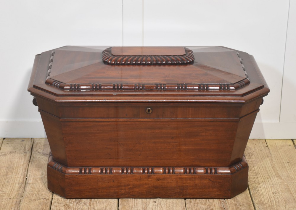 A Georgian dark mahogany sarcophagus-shaped cellarette featuring carved gadrooning around the lid and base, side handles, and a central keyhole. View VII