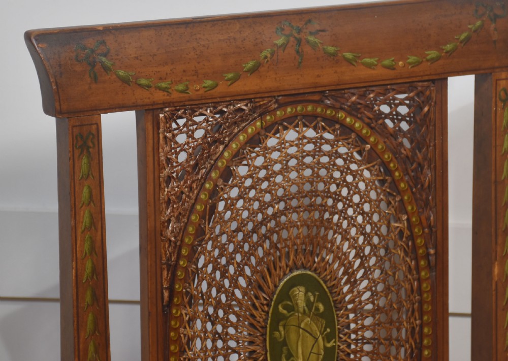 A pair of Edwardian satinwood side chairs featuring oval cane back panels with green painted central medallions, tapered legs, and pale green patterned silk seats. View VI