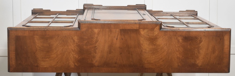 An early 20th-century walnut breakfront cabinet featuring a central solid wooden door flanked by two glazed doors, supported by bracket feet. View II