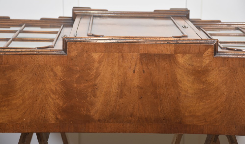 An early 20th-century walnut breakfront cabinet featuring a central solid wooden door flanked by two glazed doors, supported by bracket feet. View III