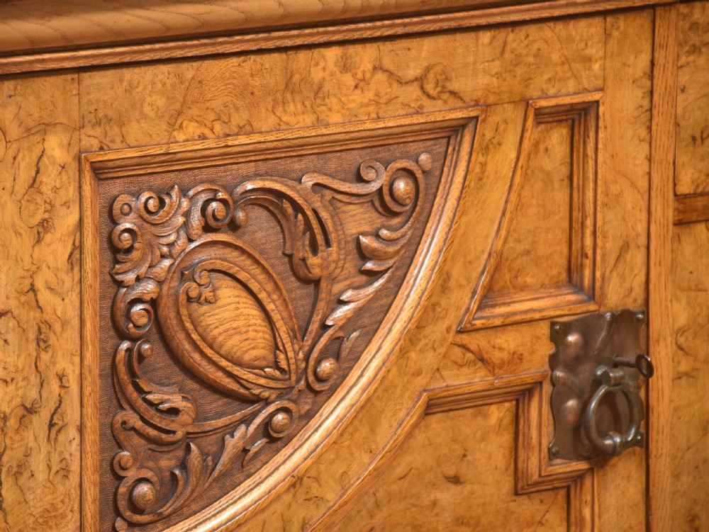 A Victorian carved pollard oak sideboard featuring an upper circular mirror back superstructure, drawers, glazed cabinet doors, and a lower pot board shelf. View XII