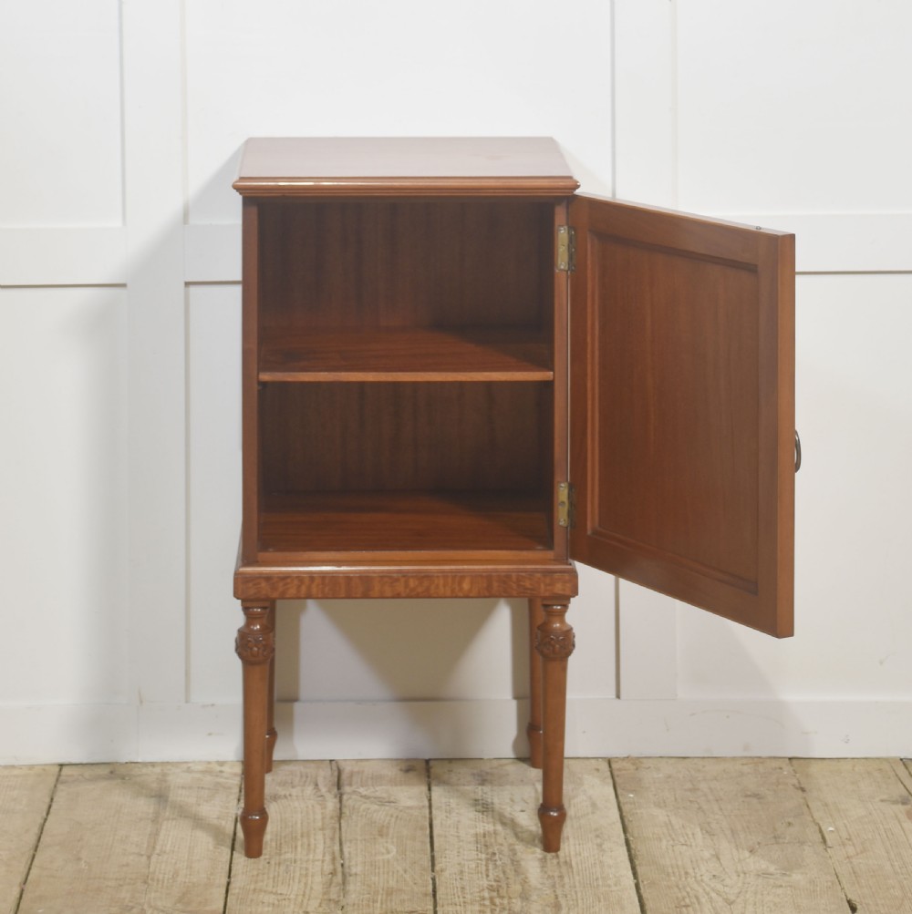 An Edwardian satinwood bedside cabinet featuring a chevron-veneered single door with an oval floral inlay and turned legs. View IV
