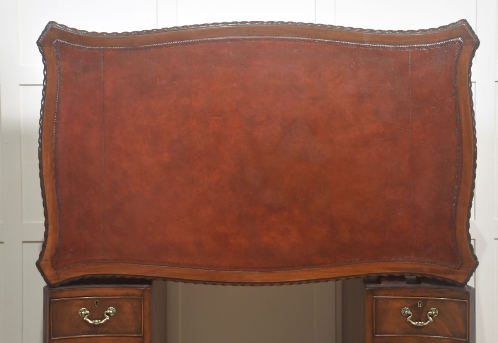 A polished mahogany twin-pedestal desk featuring brass swan-neck handles, carved edge moulding, and multiple drawers set on bracket feet. View XIII