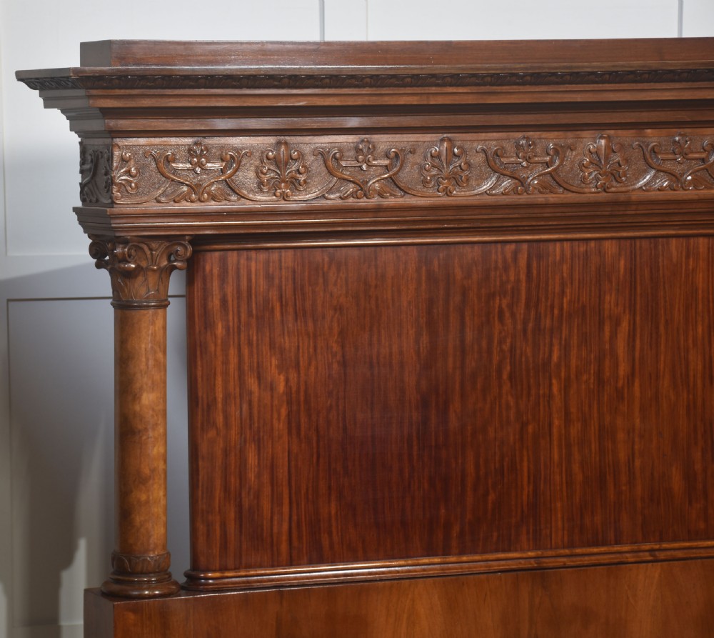 A carved mahogany super king size bed frame featuring architectural columns, a high headboard with flame mahogany panel, and carved decorative details. View VII