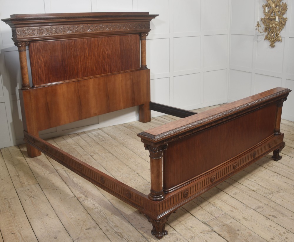 A carved mahogany super king size bed frame featuring architectural columns, a high headboard with flame mahogany panel, and carved decorative details. View VIII