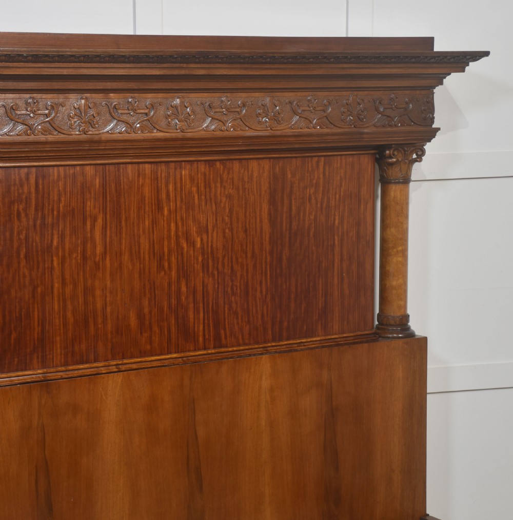 A carved mahogany super king size bed frame featuring architectural columns, a high headboard with flame mahogany panel, and carved decorative details. View XI