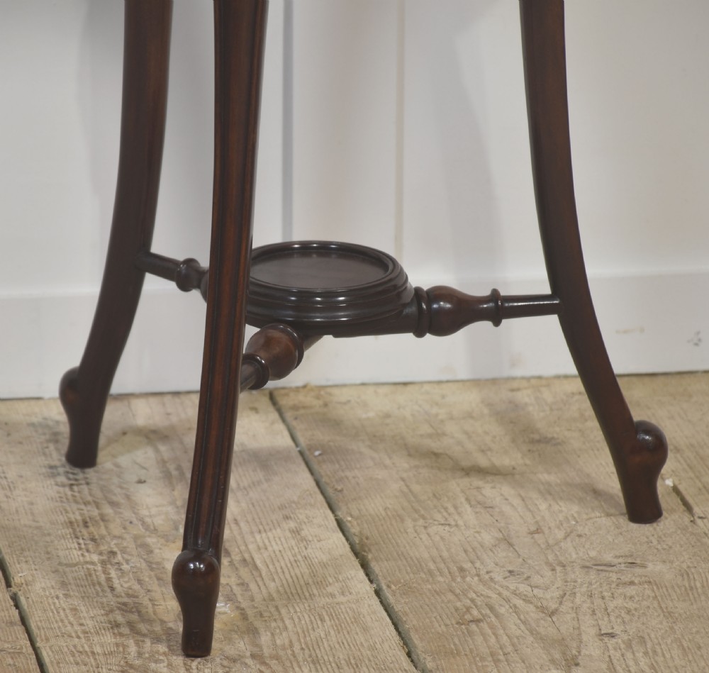 A dark mahogany wine cooler stand featuring a slatted circular bucket top with a fitted brass liner, supported by three carved legs connected by a central stretcher. View II