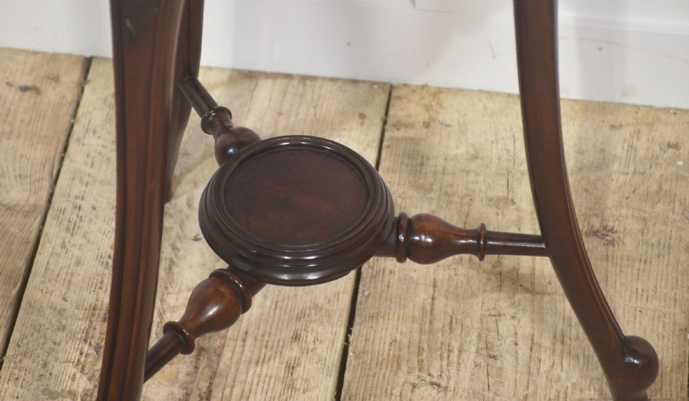 A dark mahogany wine cooler stand featuring a slatted circular bucket top with a fitted brass liner, supported by three carved legs connected by a central stretcher. View VII