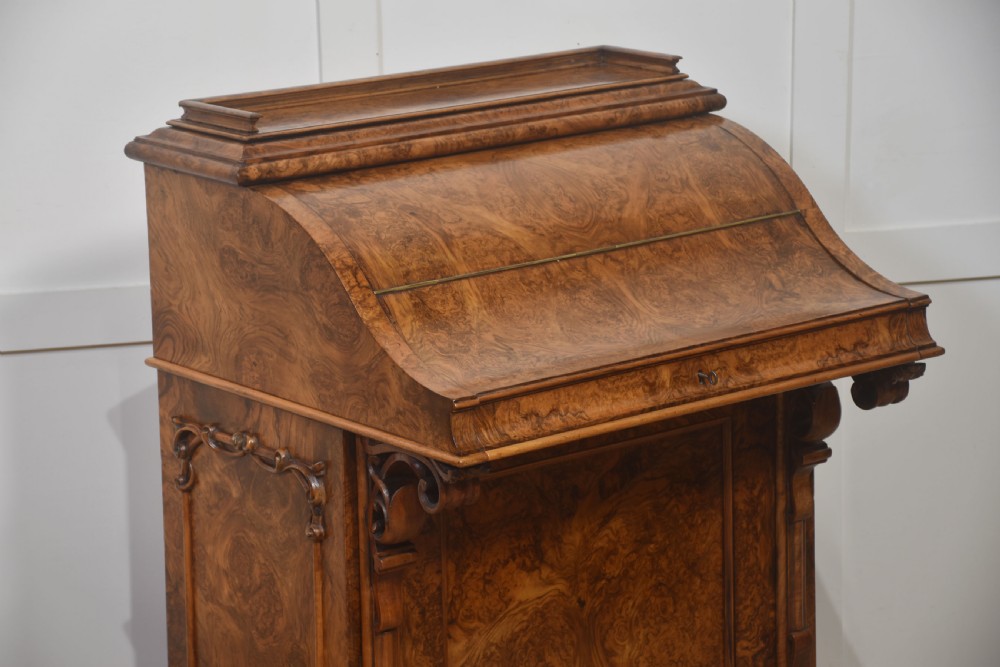 A Victorian burr walnut Davenport desk featuring a pop-up stationery cabinet decorated with floral marquetry, a sloped write top, and carved scroll supports. View III