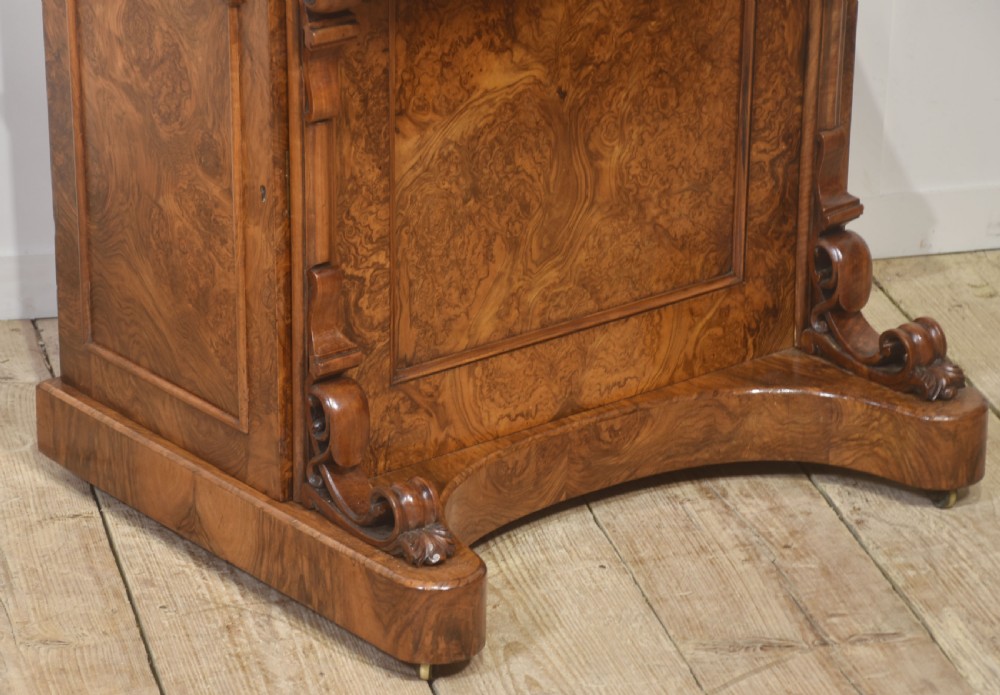 A Victorian burr walnut Davenport desk featuring a pop-up stationery cabinet decorated with floral marquetry, a sloped write top, and carved scroll supports. View IV