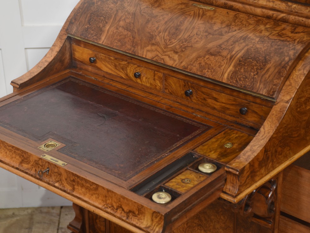 A Victorian burr walnut Davenport desk featuring a pop-up stationery cabinet decorated with floral marquetry, a sloped write top, and carved scroll supports. View VIII