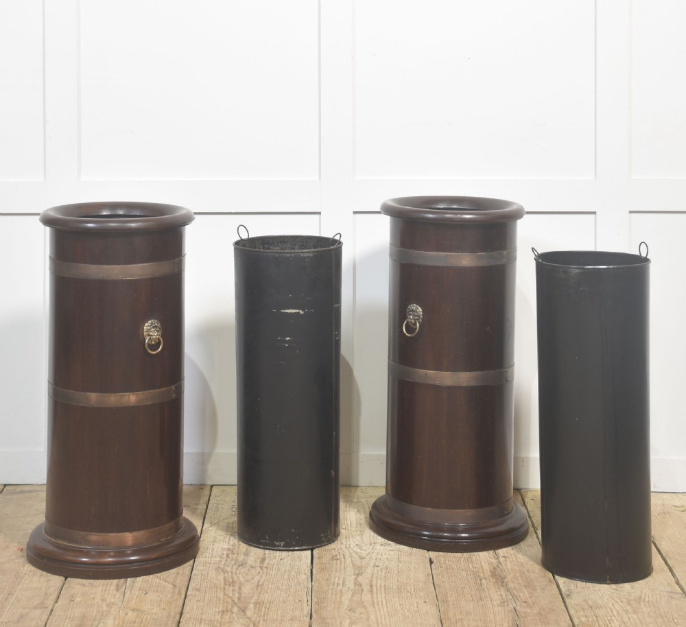A pair of cylindrical dark mahogany umbrella stands featuring brass binding bands and brass lion mask ring handles. View IV