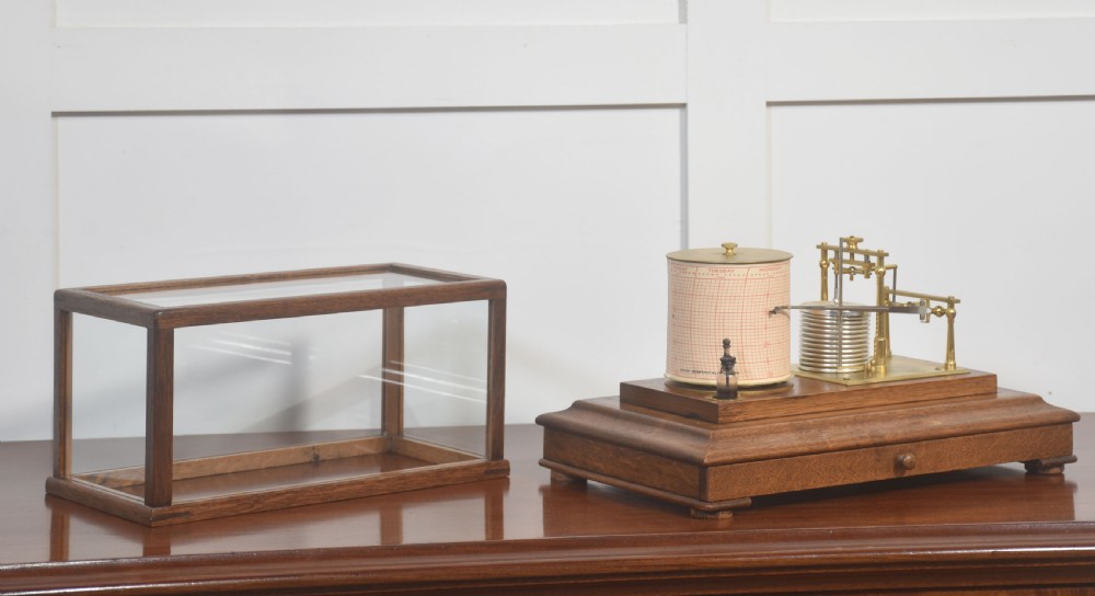 An antique barograph with a brass mechanism and paper chart drum enclosed within a glazed oak case with a bottom drawer. View III