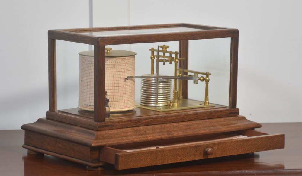 An antique barograph with a brass mechanism and paper chart drum enclosed within a glazed oak case with a bottom drawer. View V