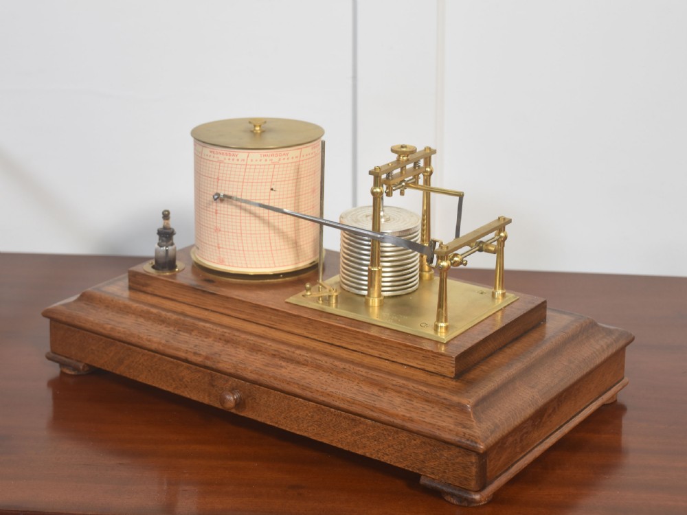 An antique barograph with a brass mechanism and paper chart drum enclosed within a glazed oak case with a bottom drawer. View VII