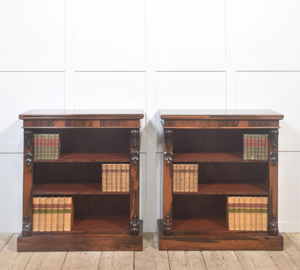 A pair of 19th-century rosewood open bookcases featuring carved side corbels and three open shelves each on a solid plinth base.