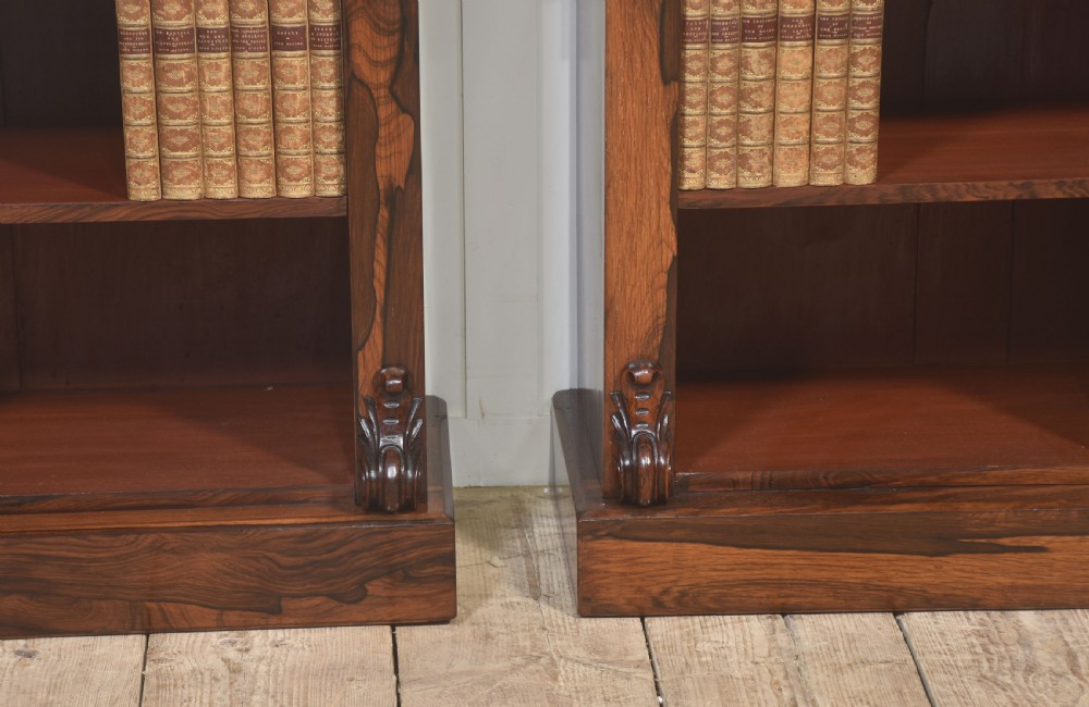 A pair of 19th-century rosewood open bookcases featuring carved side corbels and three open shelves each on a solid plinth base. View VI