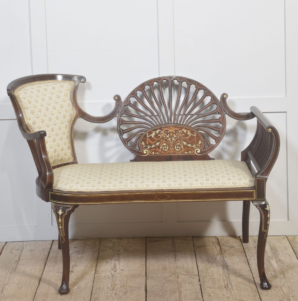 An antique mahogany settee featuring an openwork fan back with floral marquetry inlay, slatted side rails, and a cream pattern upholstered seat. View III
