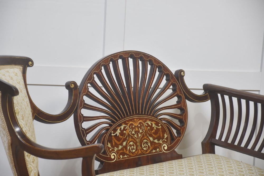 An antique mahogany settee featuring an openwork fan back with floral marquetry inlay, slatted side rails, and a cream pattern upholstered seat. View IV