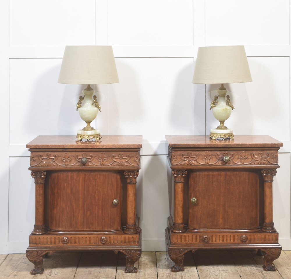 A pair of carved warm brown mahogany bedside cabinets featuring classical columns, frieze carvings, and single panel doors on carved feet. View II