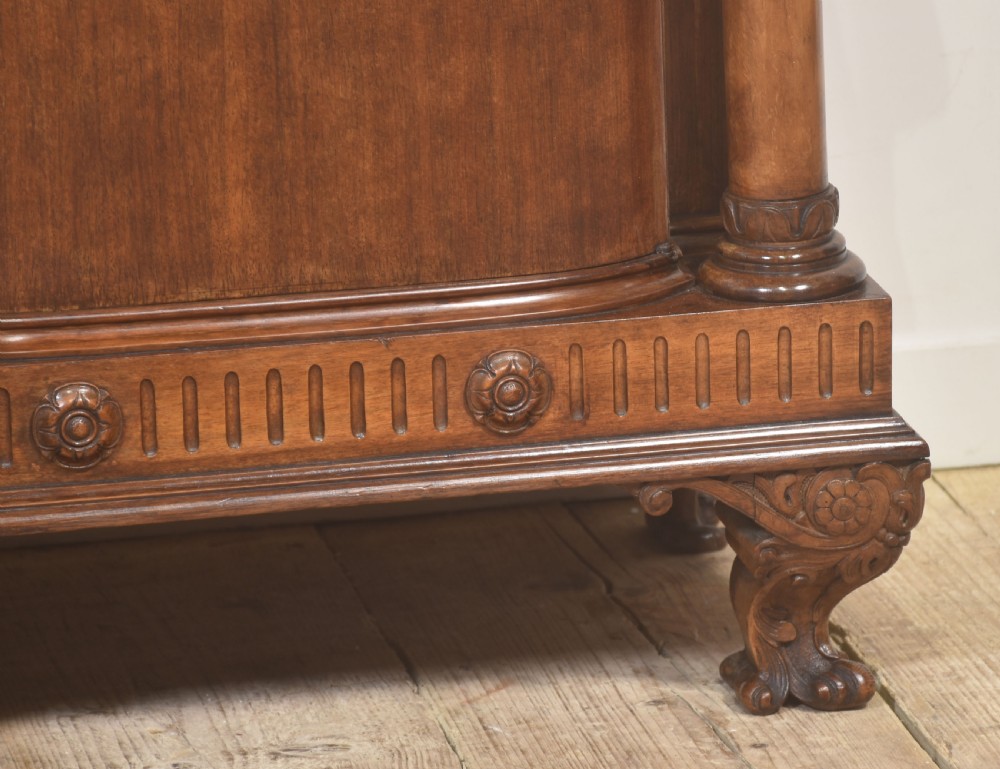 A pair of carved warm brown mahogany bedside cabinets featuring classical columns, frieze carvings, and single panel doors on carved feet. View IV