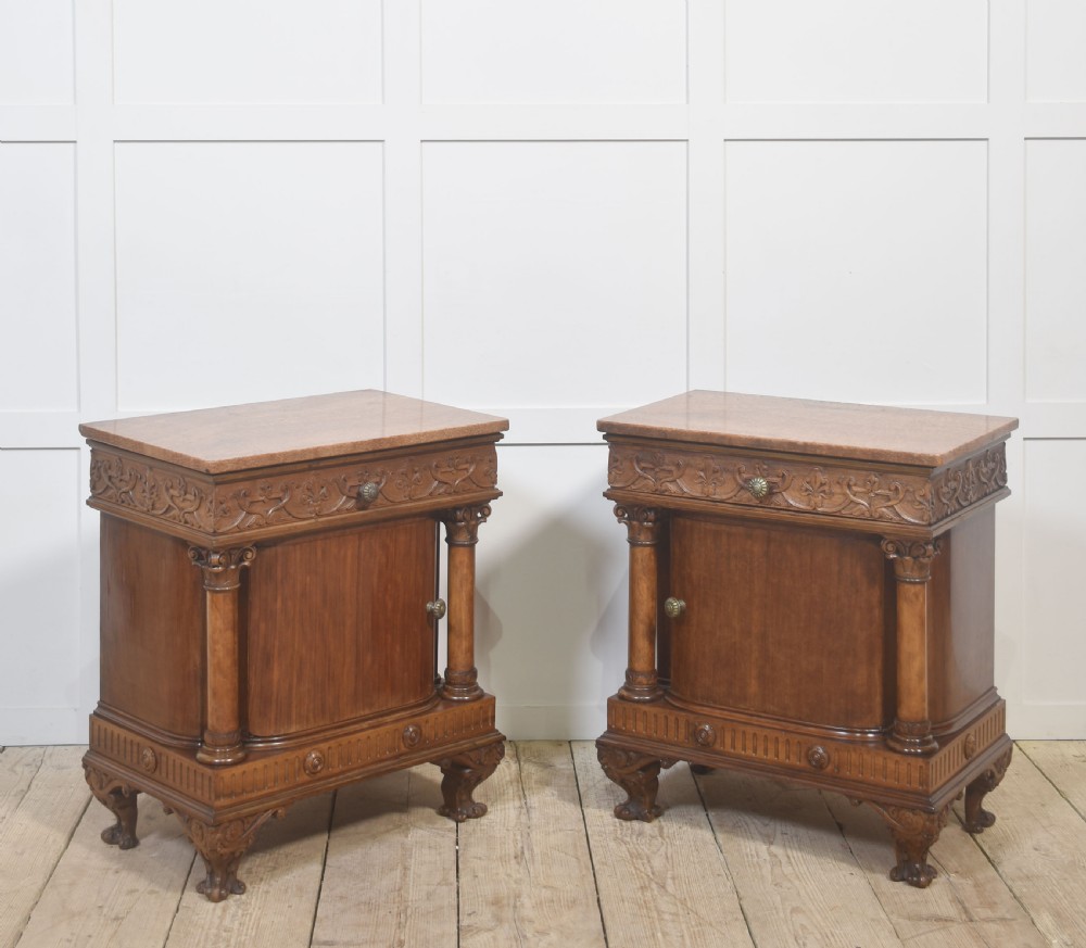 A pair of carved warm brown mahogany bedside cabinets featuring classical columns, frieze carvings, and single panel doors on carved feet. View V