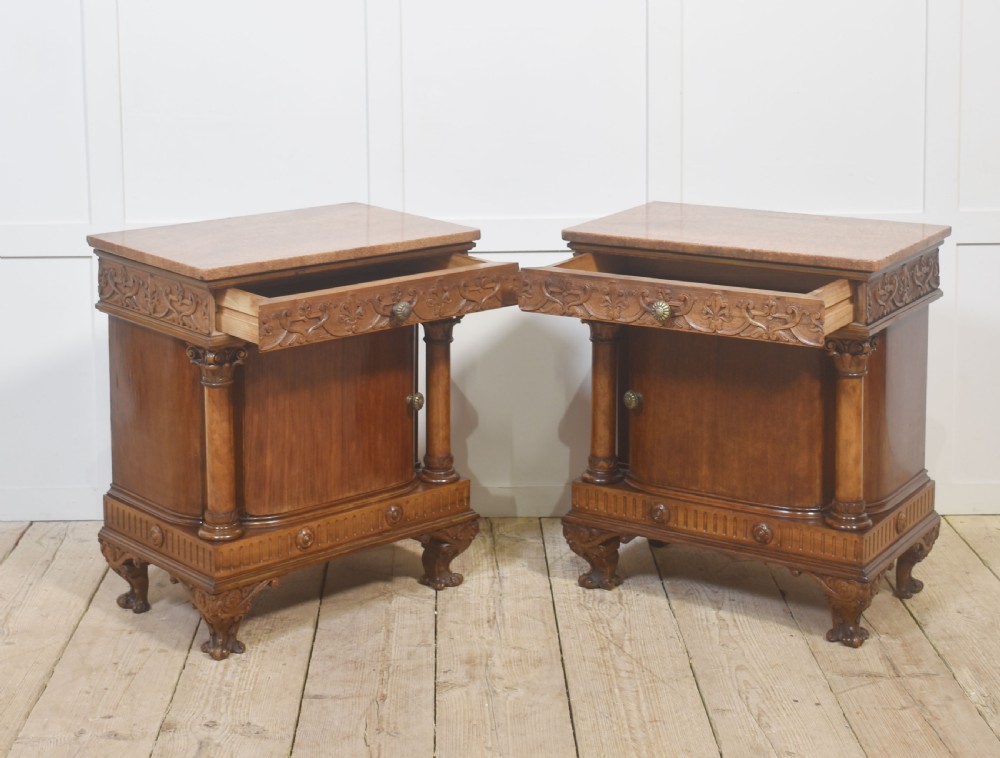 A pair of carved warm brown mahogany bedside cabinets featuring classical columns, frieze carvings, and single panel doors on carved feet. View X