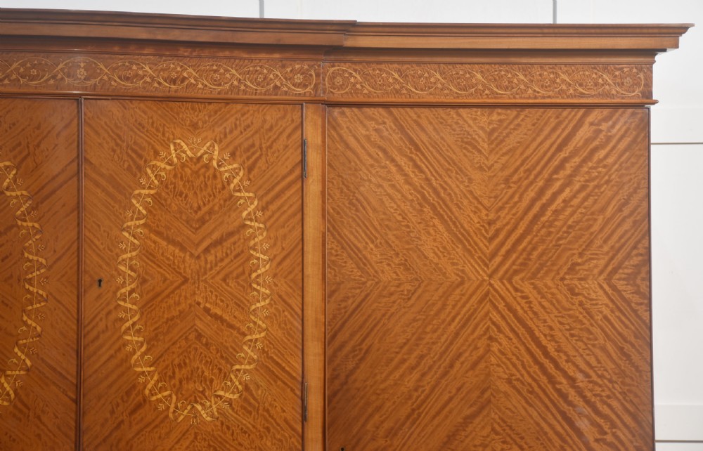 A large Edwardian inlaid satinwood compactum wardrobe featuring a central section with cupboard doors above four drawers, flanked by two full-length side doors. View II