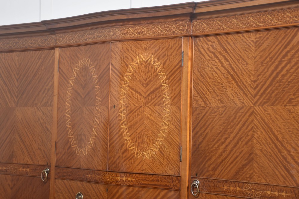 A large Edwardian inlaid satinwood compactum wardrobe featuring a central section with cupboard doors above four drawers, flanked by two full-length side doors. View VIII