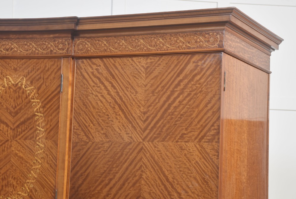 A large Edwardian inlaid satinwood compactum wardrobe featuring a central section with cupboard doors above four drawers, flanked by two full-length side doors. View X