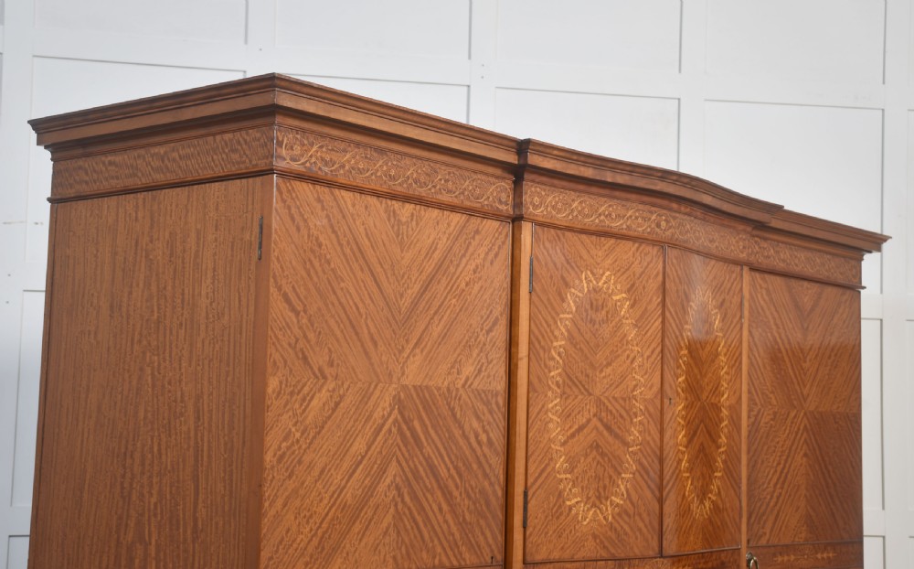 A large Edwardian inlaid satinwood compactum wardrobe featuring a central section with cupboard doors above four drawers, flanked by two full-length side doors. View XII