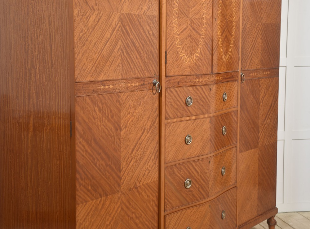 A large Edwardian inlaid satinwood compactum wardrobe featuring a central section with cupboard doors above four drawers, flanked by two full-length side doors. View XIII