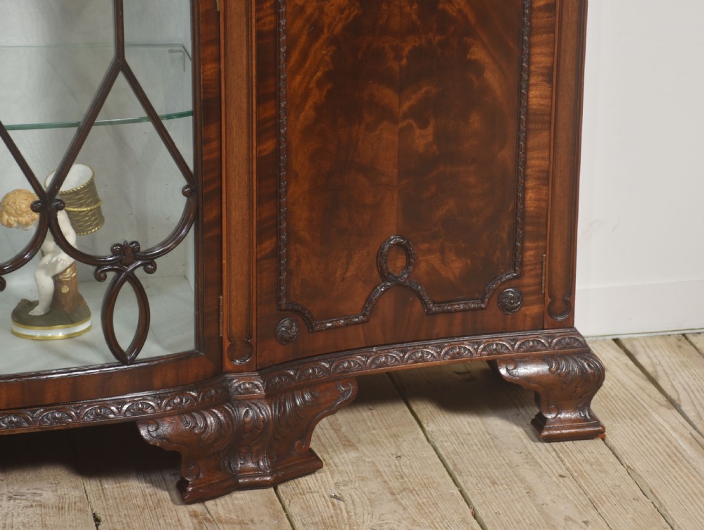 A wide mahogany display cabinet featuring flame mahogany veneered side doors, central astragal glazed double doors, carved rosettes along the frieze, and cabriole feet. View V