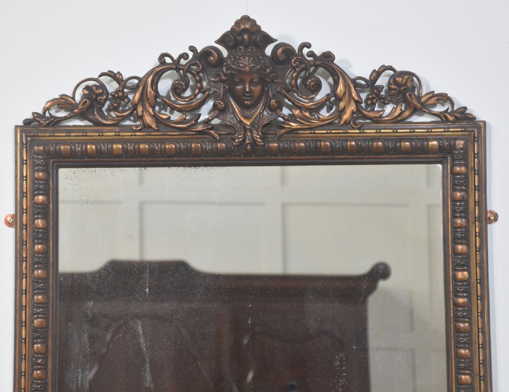 A large rectangular Neoclassical wall mirror featuring a carved giltwood frame topped with a decorative mascaron and acanthus scroll crest. View IV