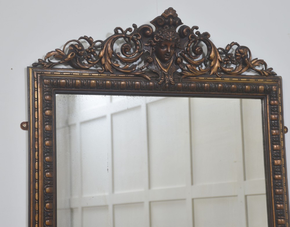 A large rectangular Neoclassical wall mirror featuring a carved giltwood frame topped with a decorative mascaron and acanthus scroll crest. View VI
