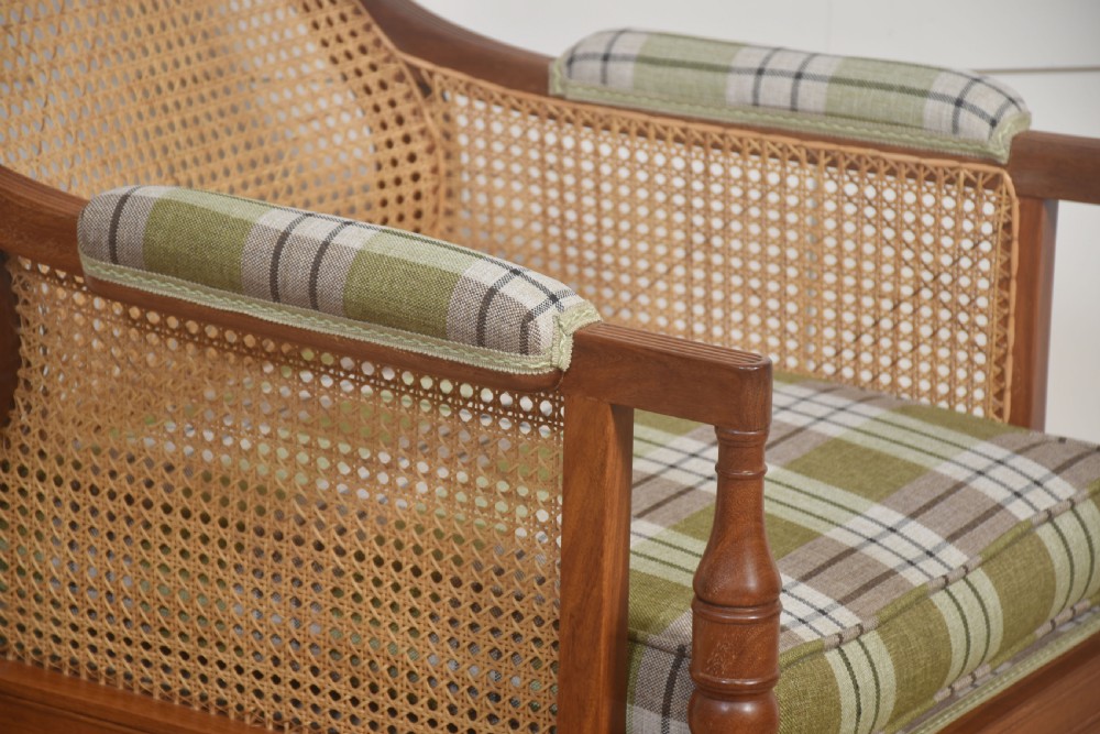 A mahogany bergere armchair featuring woven cane side and back panels, turned front legs on castors, and green plaid cushion upholstery. View VIII