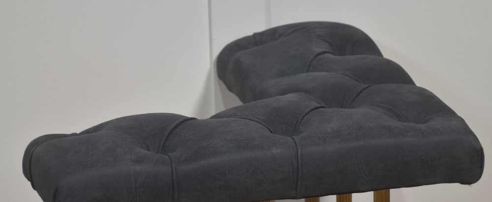 A solid brass club fender featuring twin button-upholstered grey corner seats supported by vertical brass spindles and a dipped central railing. View III