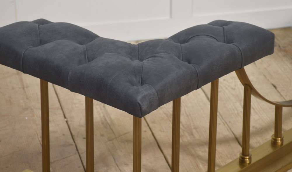 A solid brass club fender featuring twin button-upholstered grey corner seats supported by vertical brass spindles and a dipped central railing. View VI