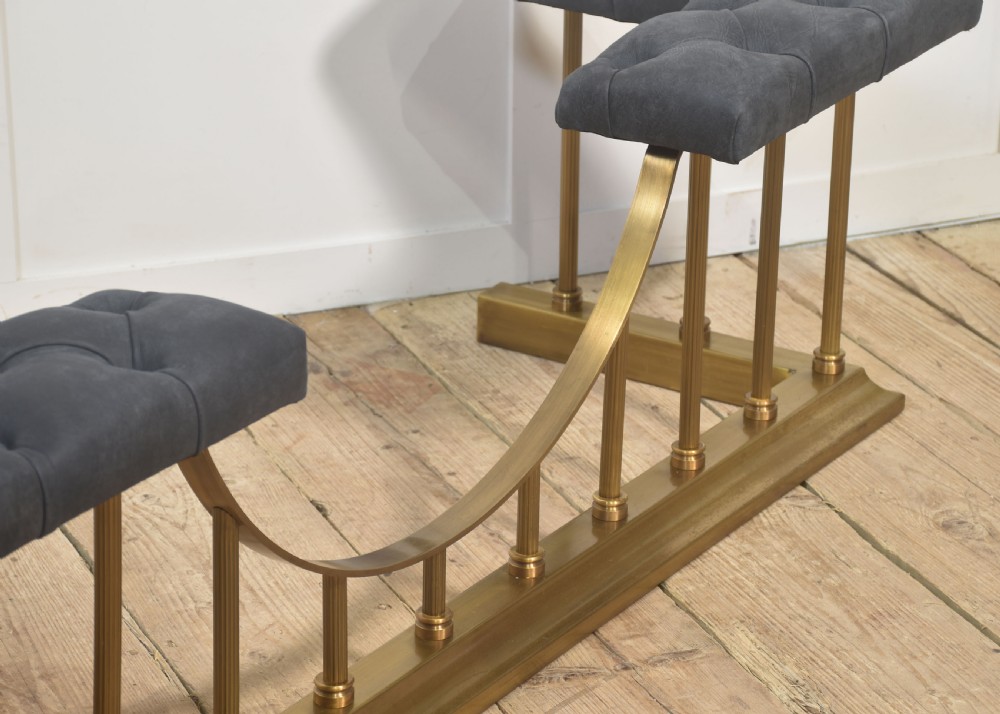 A solid brass club fender featuring twin button-upholstered grey corner seats supported by vertical brass spindles and a dipped central railing. View VII
