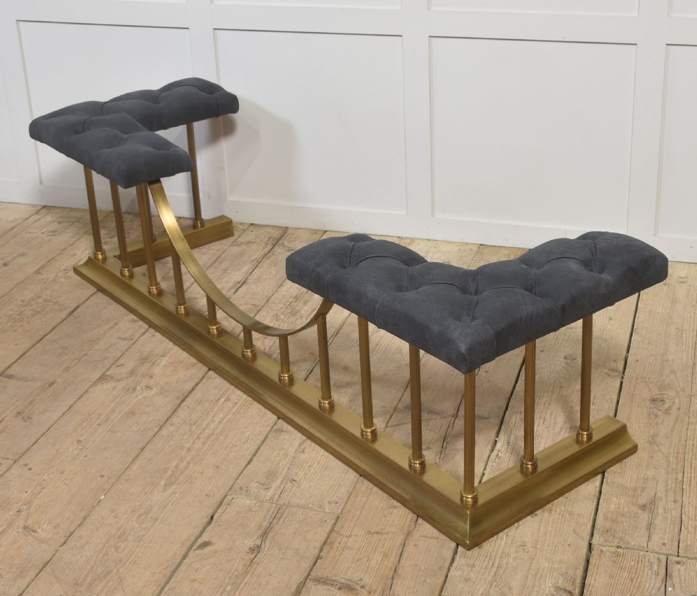 A solid brass club fender featuring twin button-upholstered grey corner seats supported by vertical brass spindles and a dipped central railing. View IX