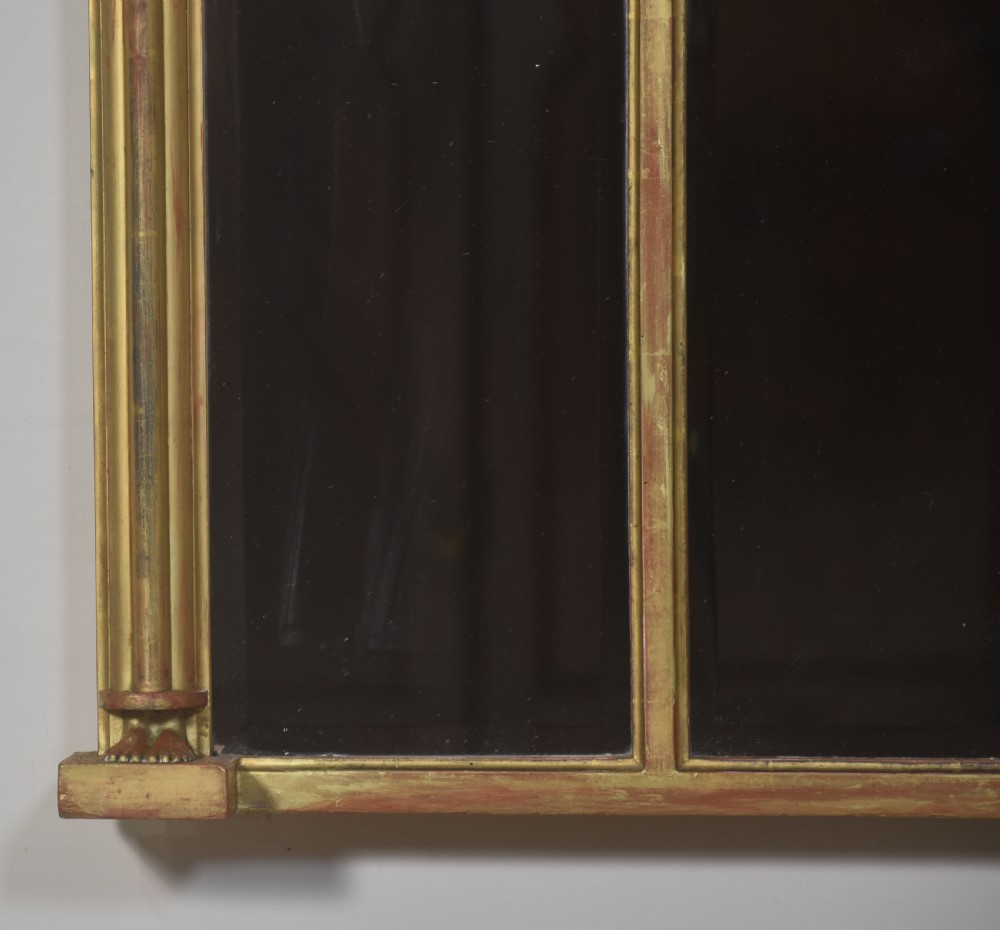 A large rectangular Neoclassical giltwood overmantel mirror featuring a three-plate glass design, frieze with spherule moulding and central shell motif, flanked by fluted side columns. View III
