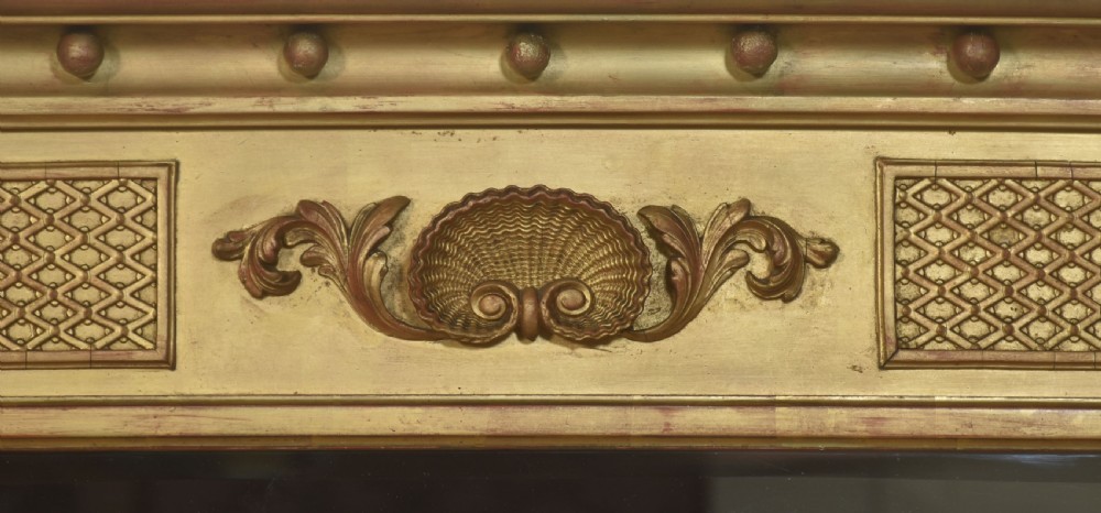 A large rectangular Neoclassical giltwood overmantel mirror featuring a three-plate glass design, frieze with spherule moulding and central shell motif, flanked by fluted side columns. View IV