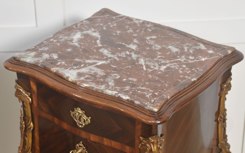 A pair of French Louis XV style bedside cabinets crafted with kingwood parquetry, dark marble tops, cabriole legs, and bronze mounts. View II