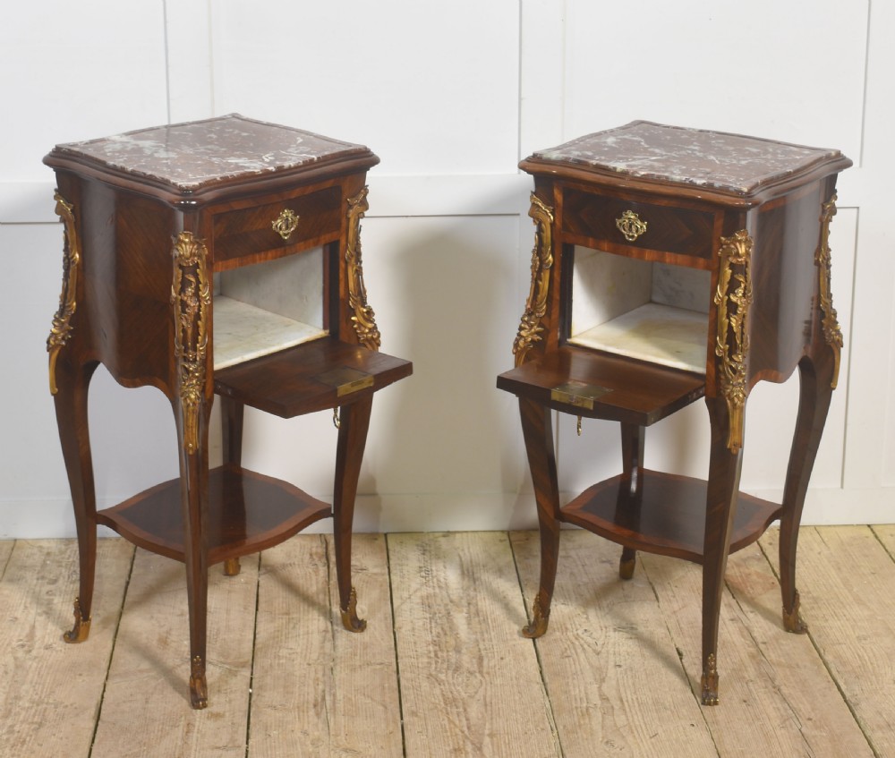 A pair of French Louis XV style bedside cabinets crafted with kingwood parquetry, dark marble tops, cabriole legs, and bronze mounts. View VI