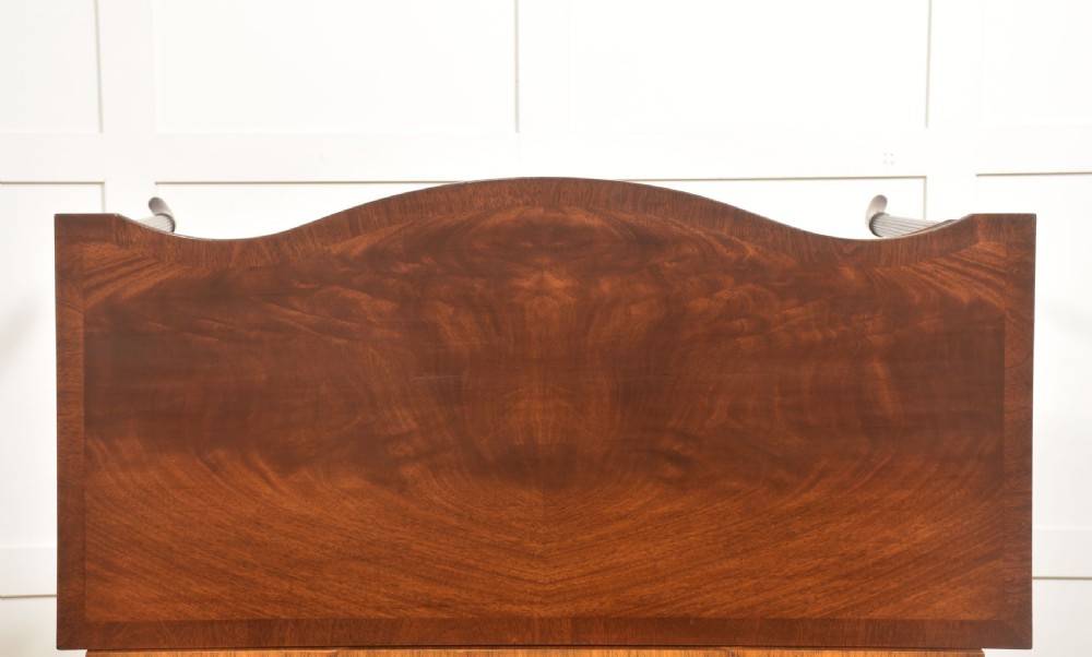 An inlaid mahogany writing table featuring a serpentine front, drawers with brass ring handles, oval patera marquetry, and fluted legs. View XI